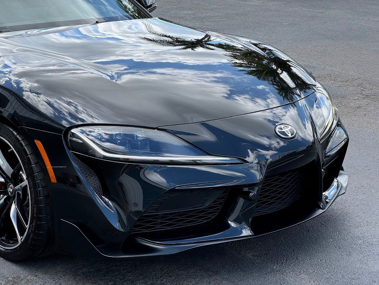 Black Toyota Supra sports car, front view, outdoors.