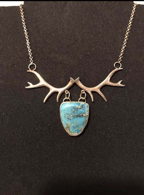 A necklace with antlers and a turquoise pendant