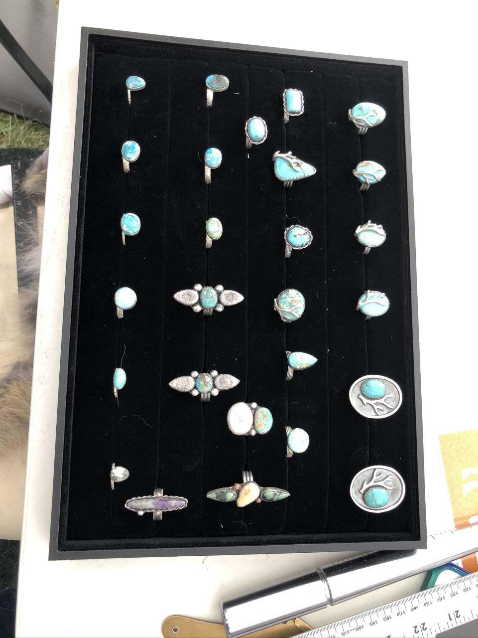 A black tray filled with turquoise and silver rings