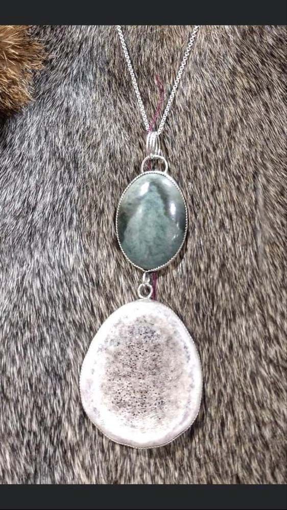 A close up of a necklace with two pendants on a furry surface.