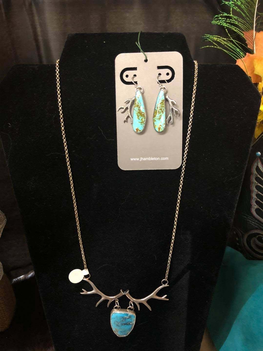 A necklace and earrings set on a black mannequin