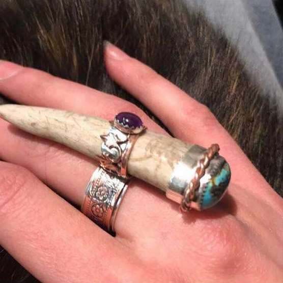 A woman 's hand with three rings on it