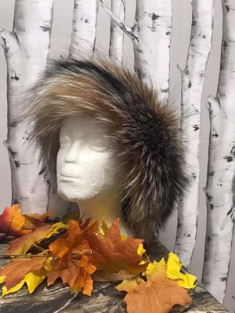 A mannequin head wearing a fur hat with leaves around it.