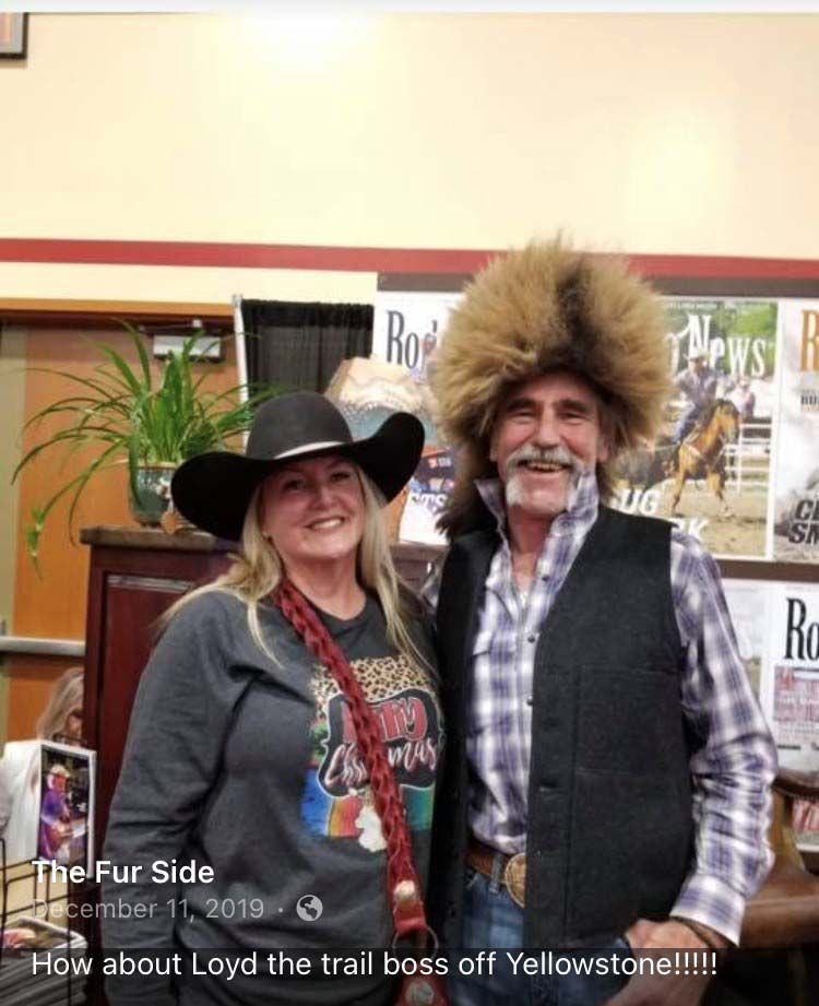 A man and a woman are posing for a picture . the man is wearing a fur hat.