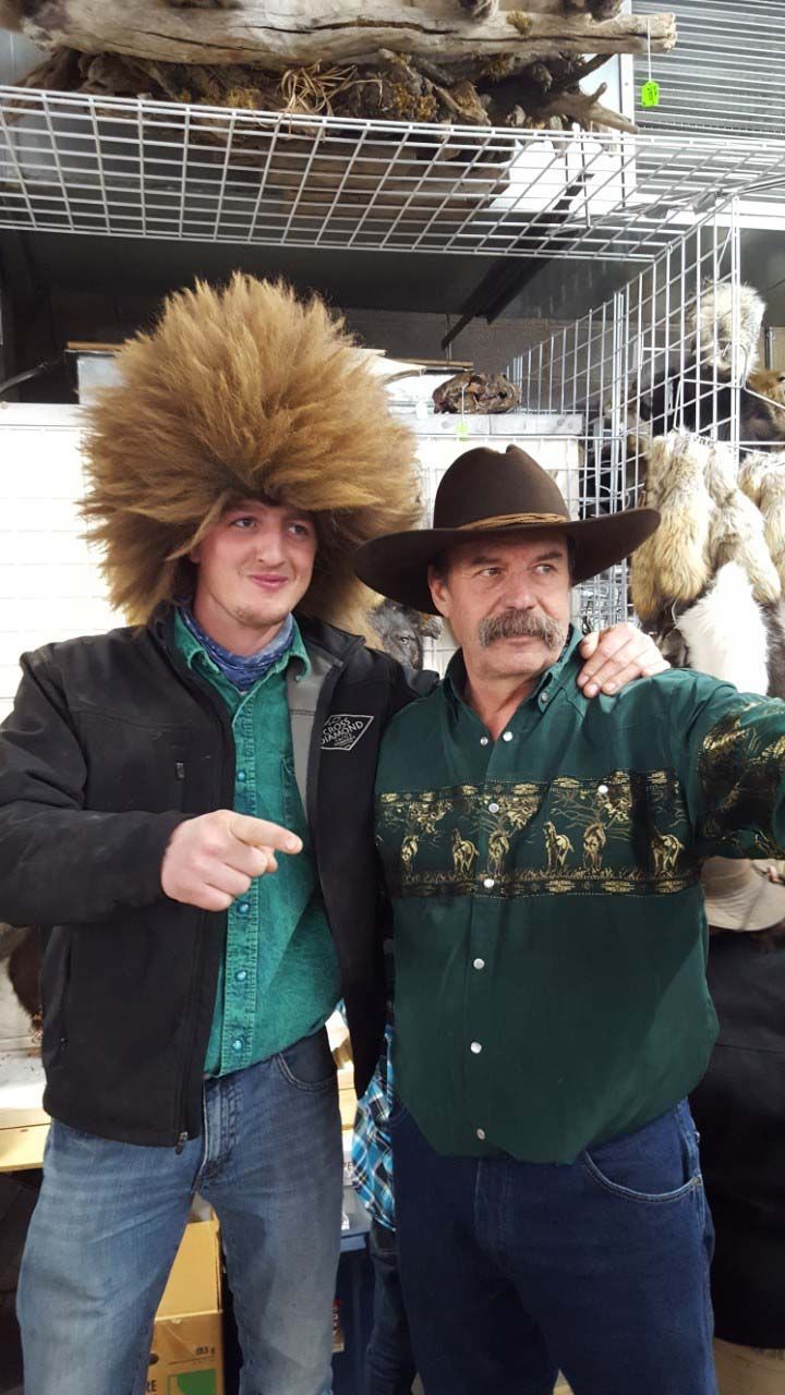 Two men are posing for a picture in front of a display of stuffed animals.