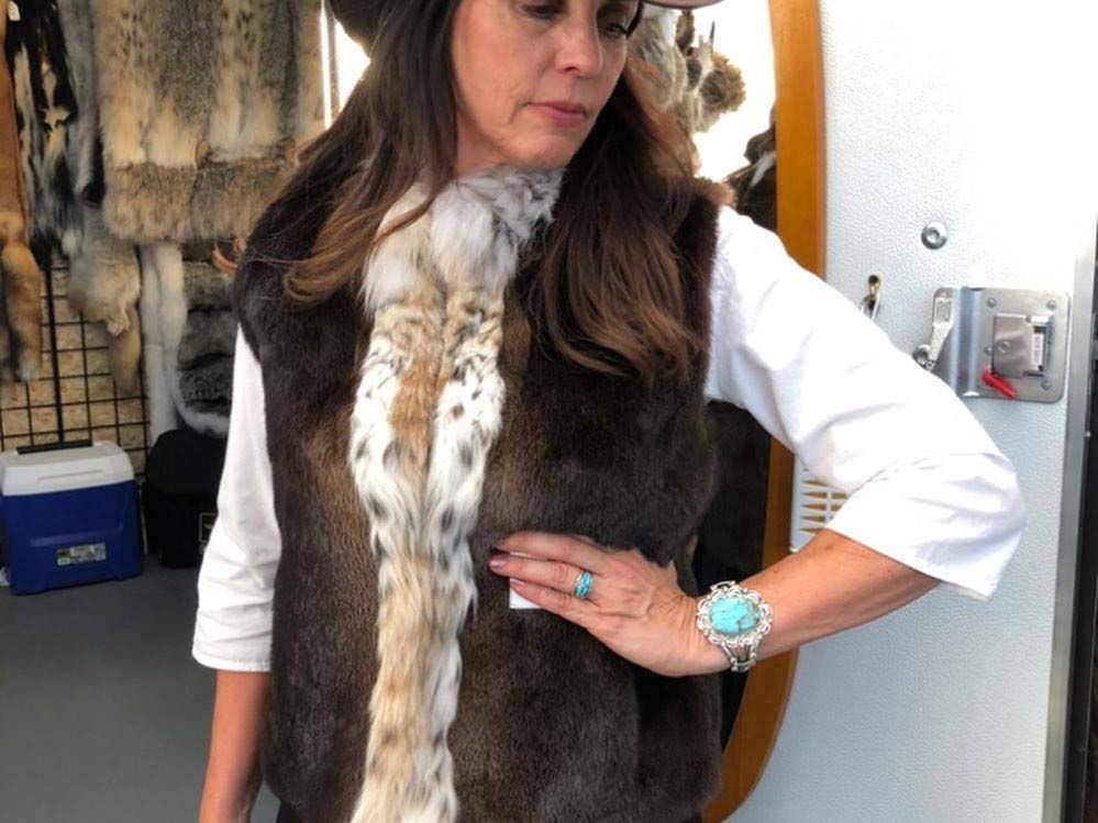 A woman wearing a hat and a fur vest