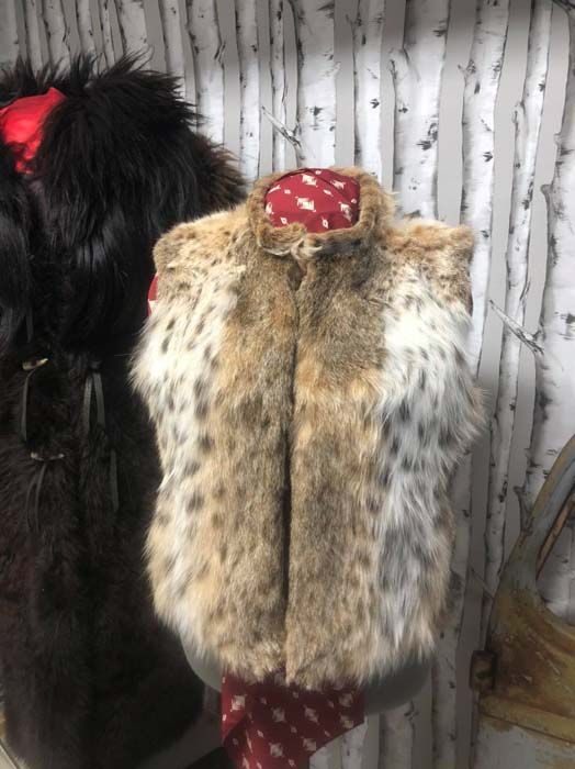 A fur vest is hanging on a mannequin.