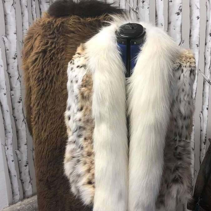 Two fur coats , one brown and one white , are on a mannequin.