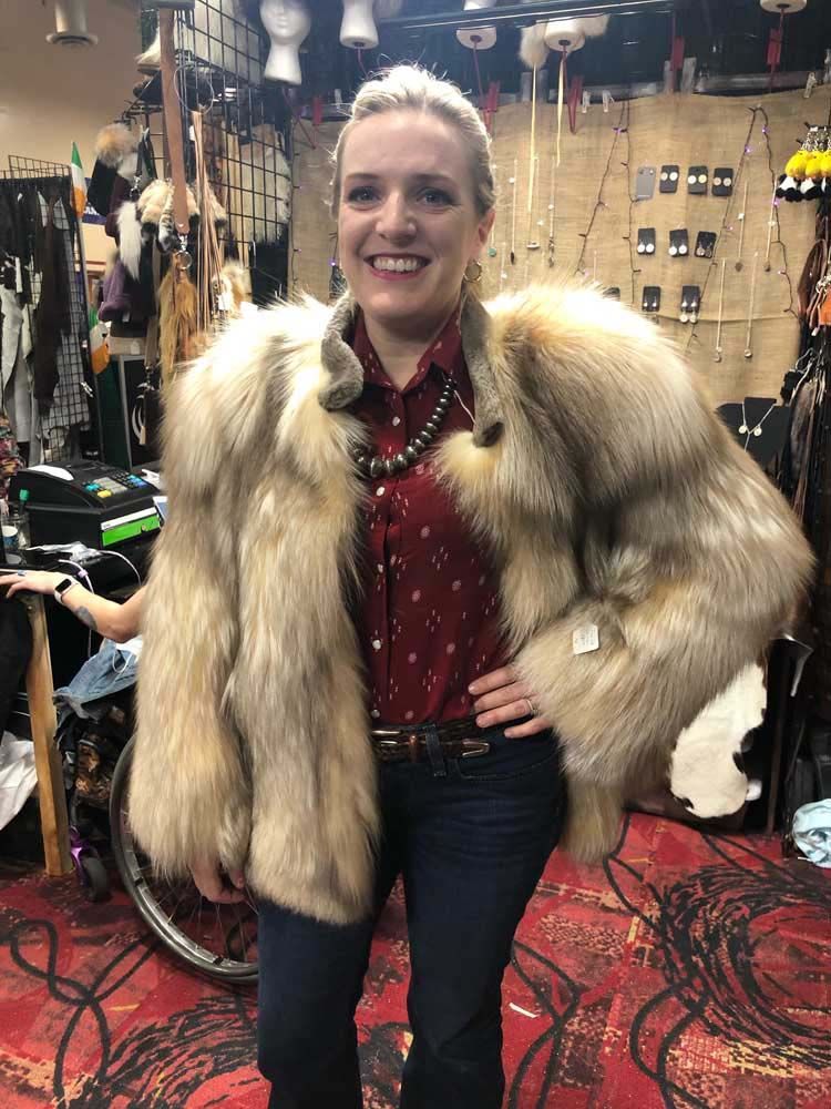 A woman wearing a fur coat is standing in a room.