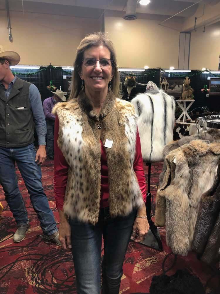 A woman wearing a fur vest is standing in a room.