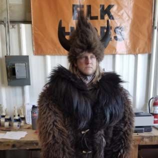 A man in a fur coat and horns is standing in front of a sign.
