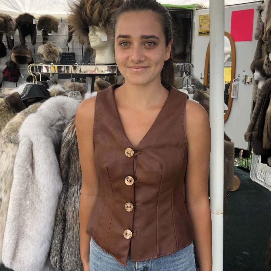 A woman wearing a brown leather vest and jeans
