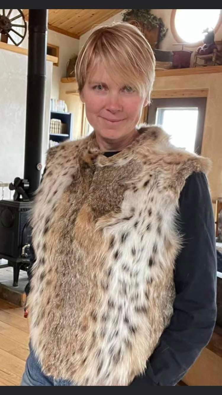 A woman is wearing a fur vest in a living room.