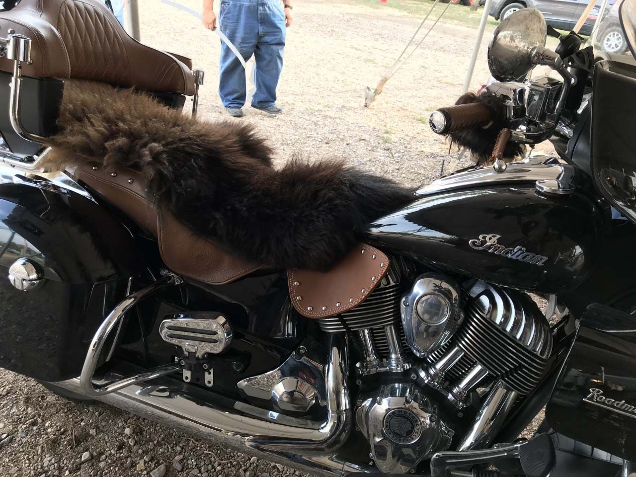 A black motorcycle with a fur cushion on the seat.