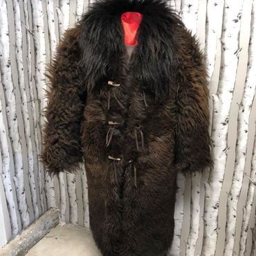 A brown fur coat with a black collar is hanging on a mannequin.
