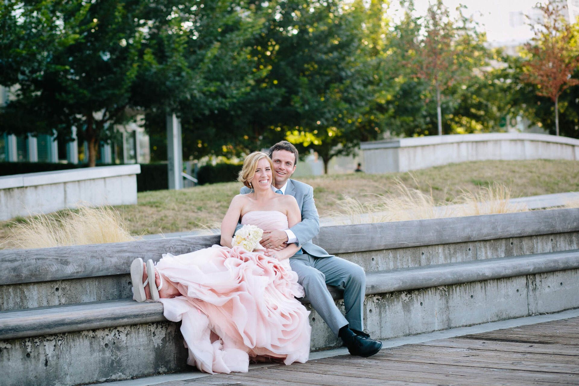Bride and groom sitting on a bench in the park