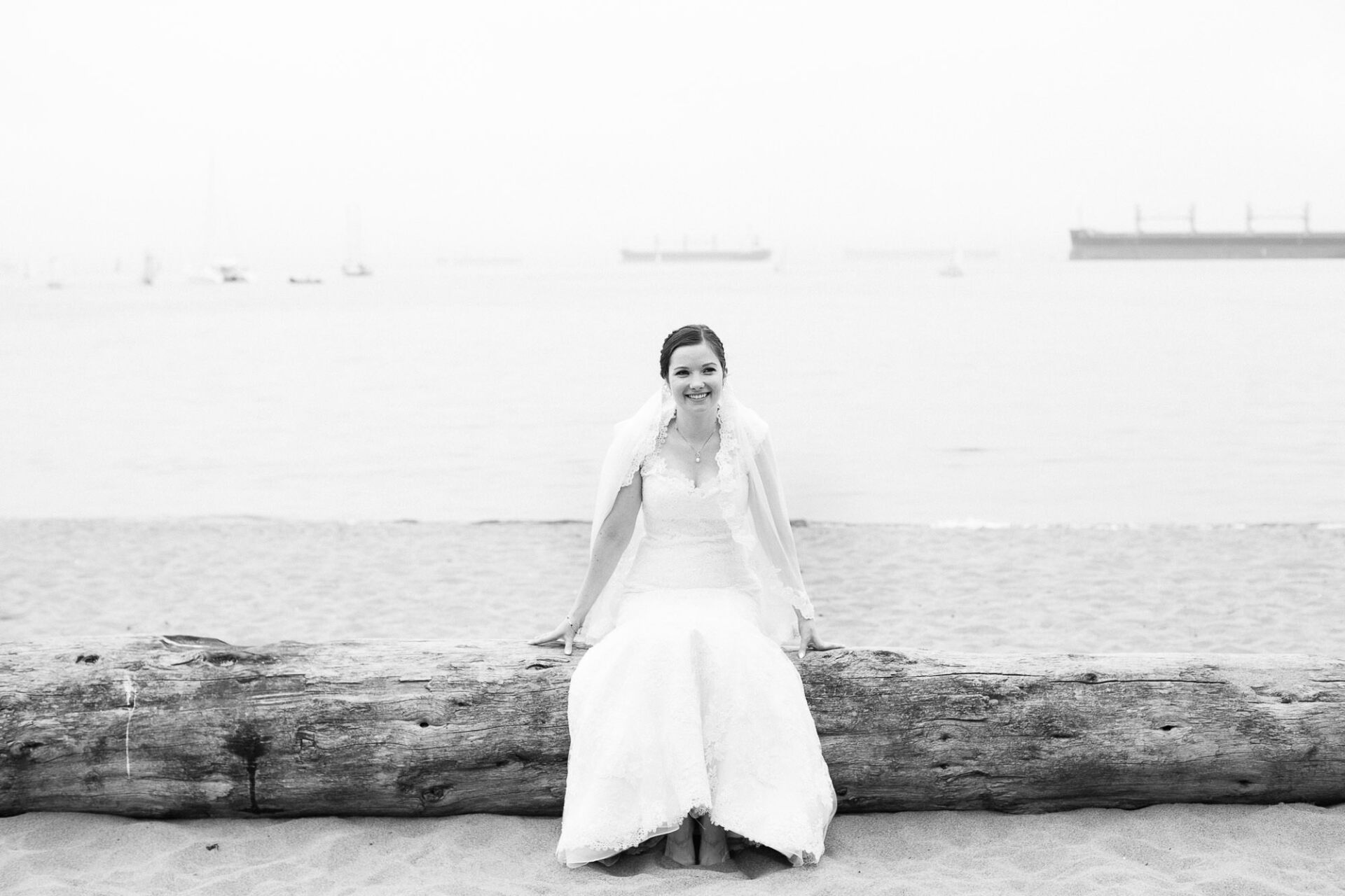 Bride sitting on a log by the ocean