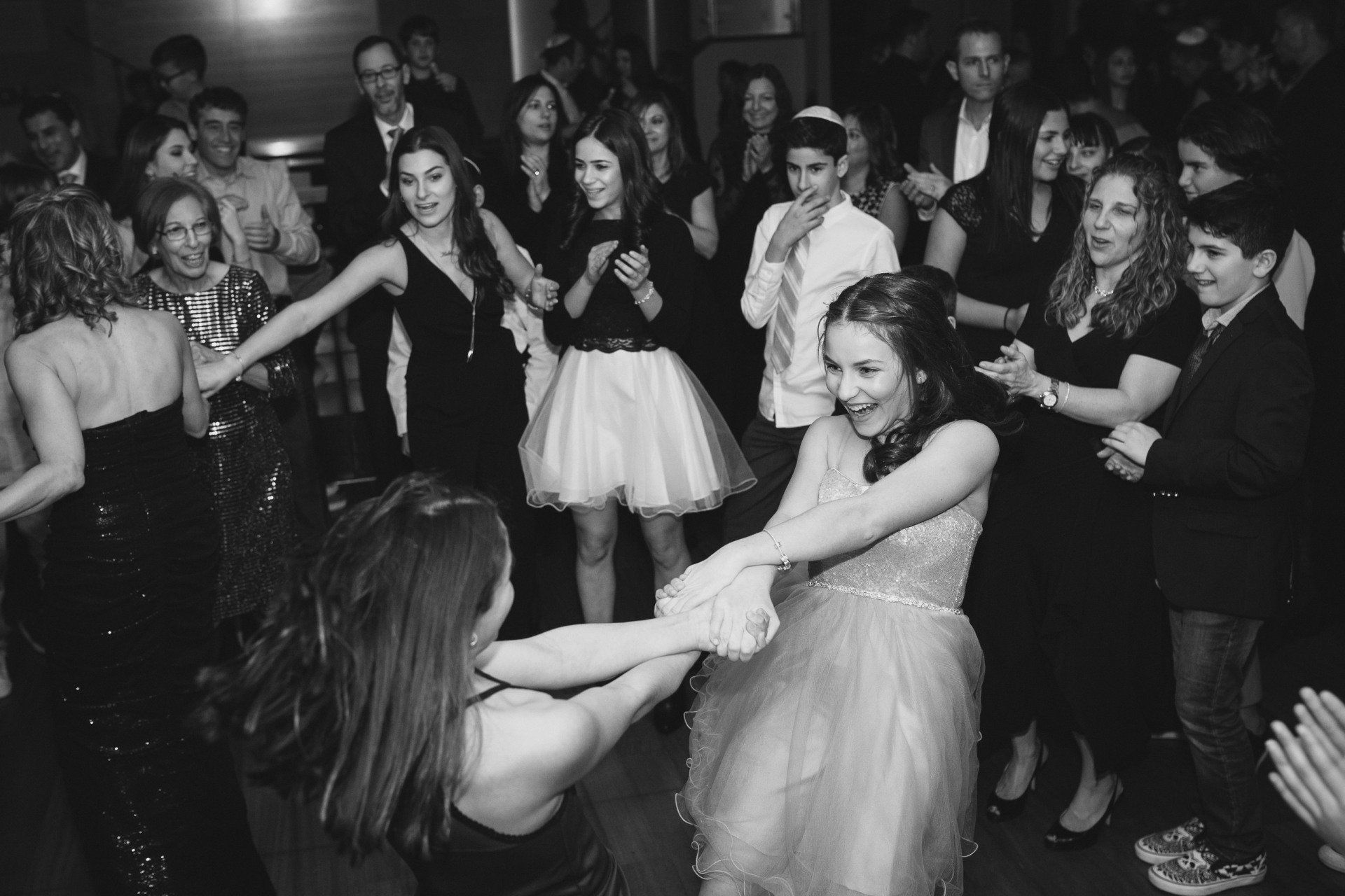 Two girls swinging each other around on the dance floor at a bat mitzvah