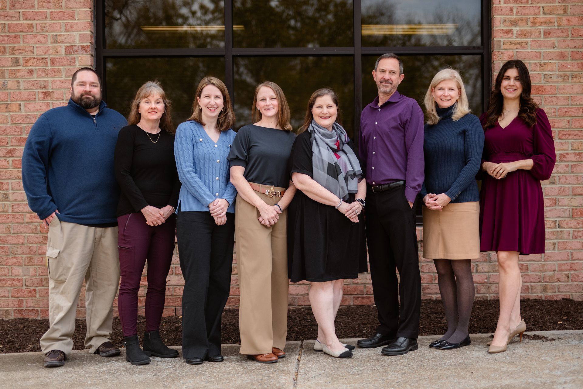 A group of people are posing for a picture in front of a brick building.