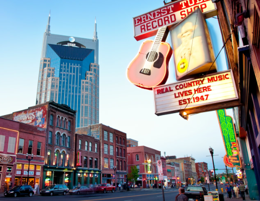 Downtown street with Ernest Tubb Record Shop sign and a blue-topped skyscraper at dusk