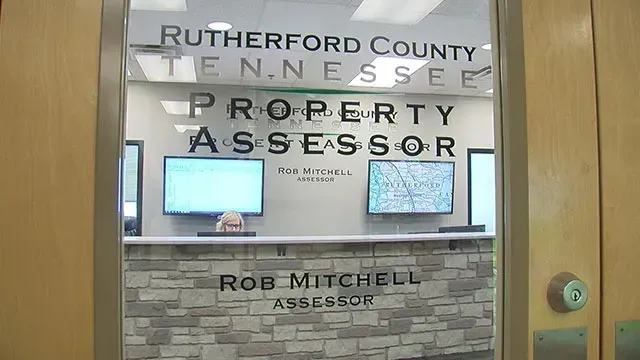 Rutherford County, Tennessee property assessor office sign behind a glass door with a stone wall and monitors inside
