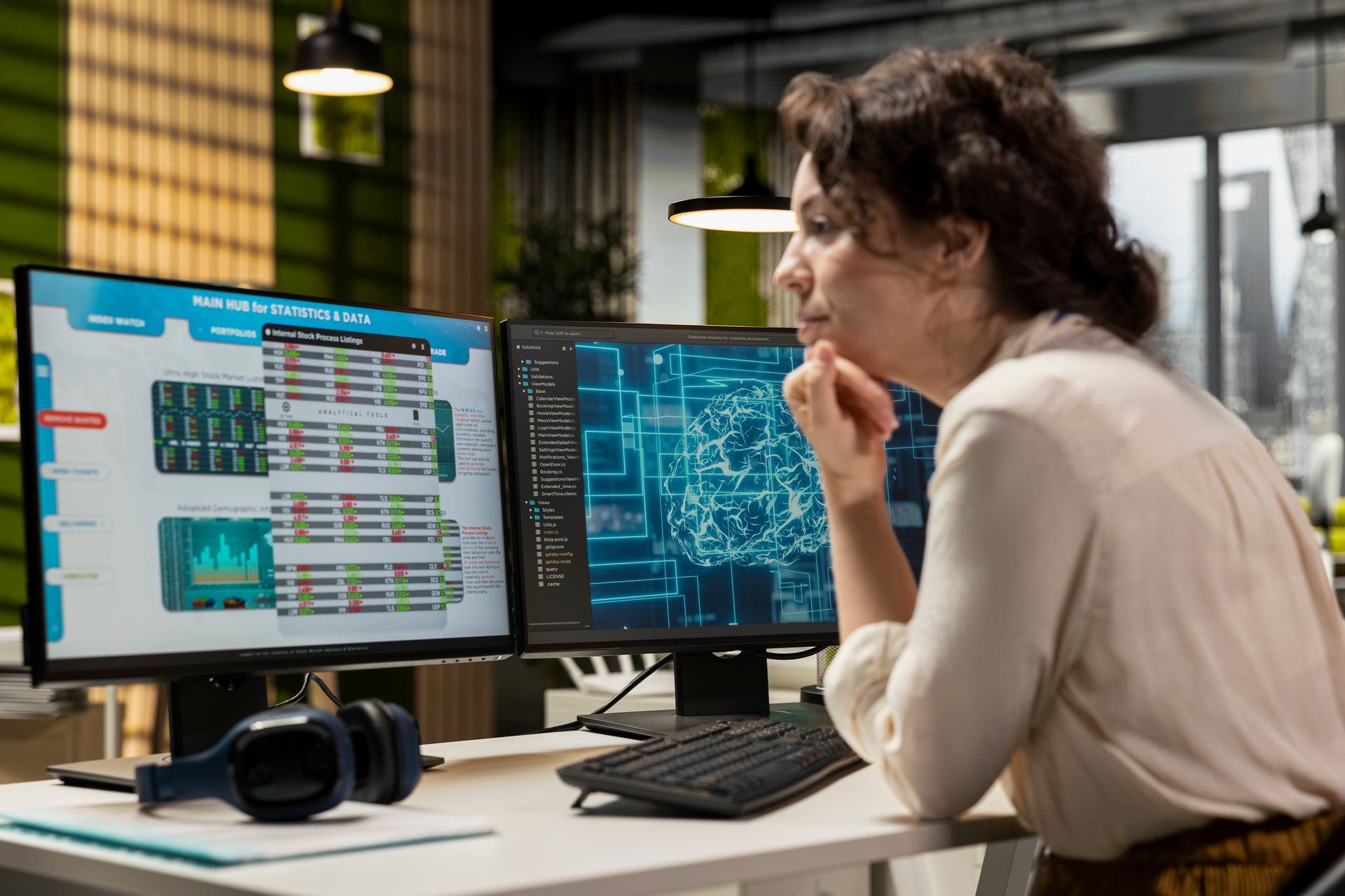 Woman looking at two computer screens displaying data, in an office setting. Woman looking at two computer screens displaying data, in an office setting.