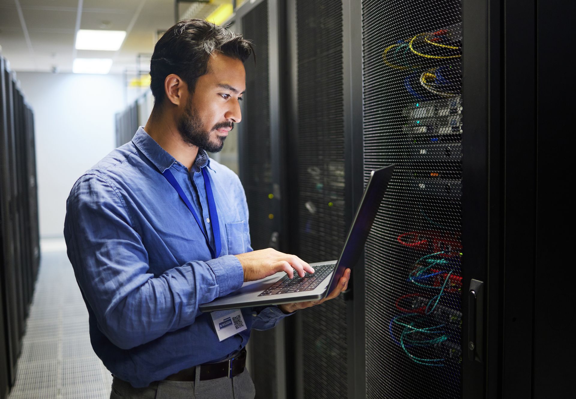 Technician using a laptop, inspecting servers in a data center. Technician using a laptop, inspecting servers in a data center.