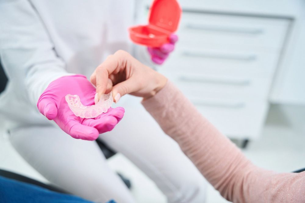 A Dentist Is Giving A Patient A Dental Retainer — Highlands Denture Clinic in Willow Vale, NSW