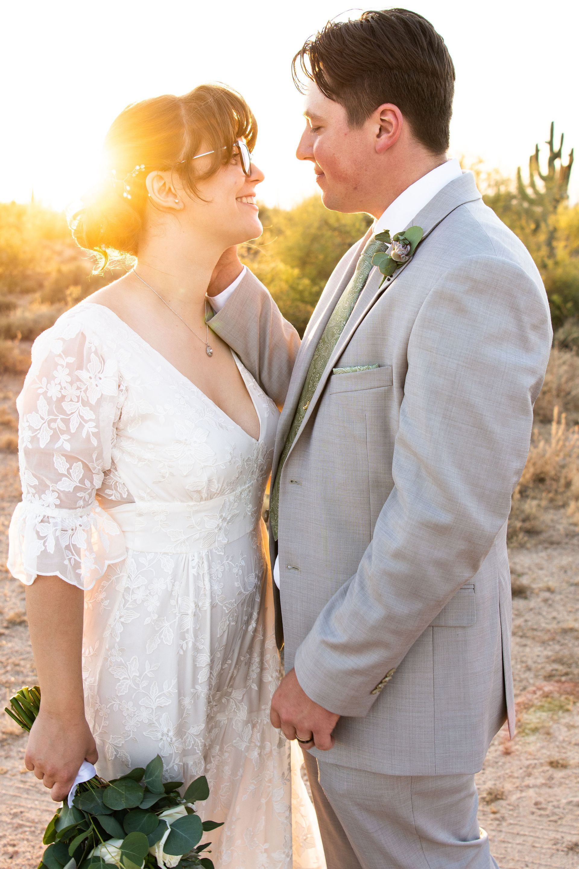 A bride and groom are looking at each other in the desert.
