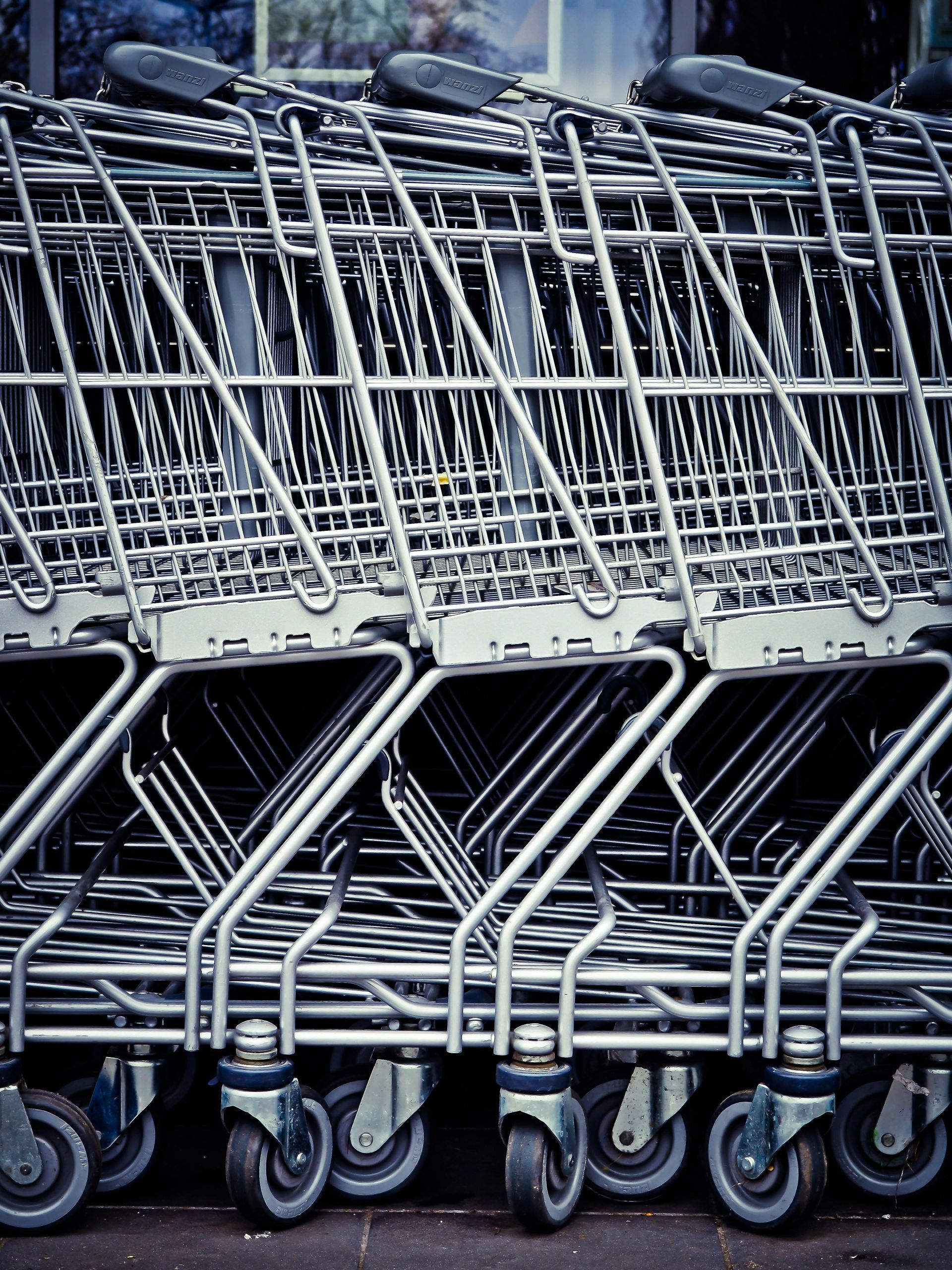 Row of silver shopping carts with black wheels, stacked together.