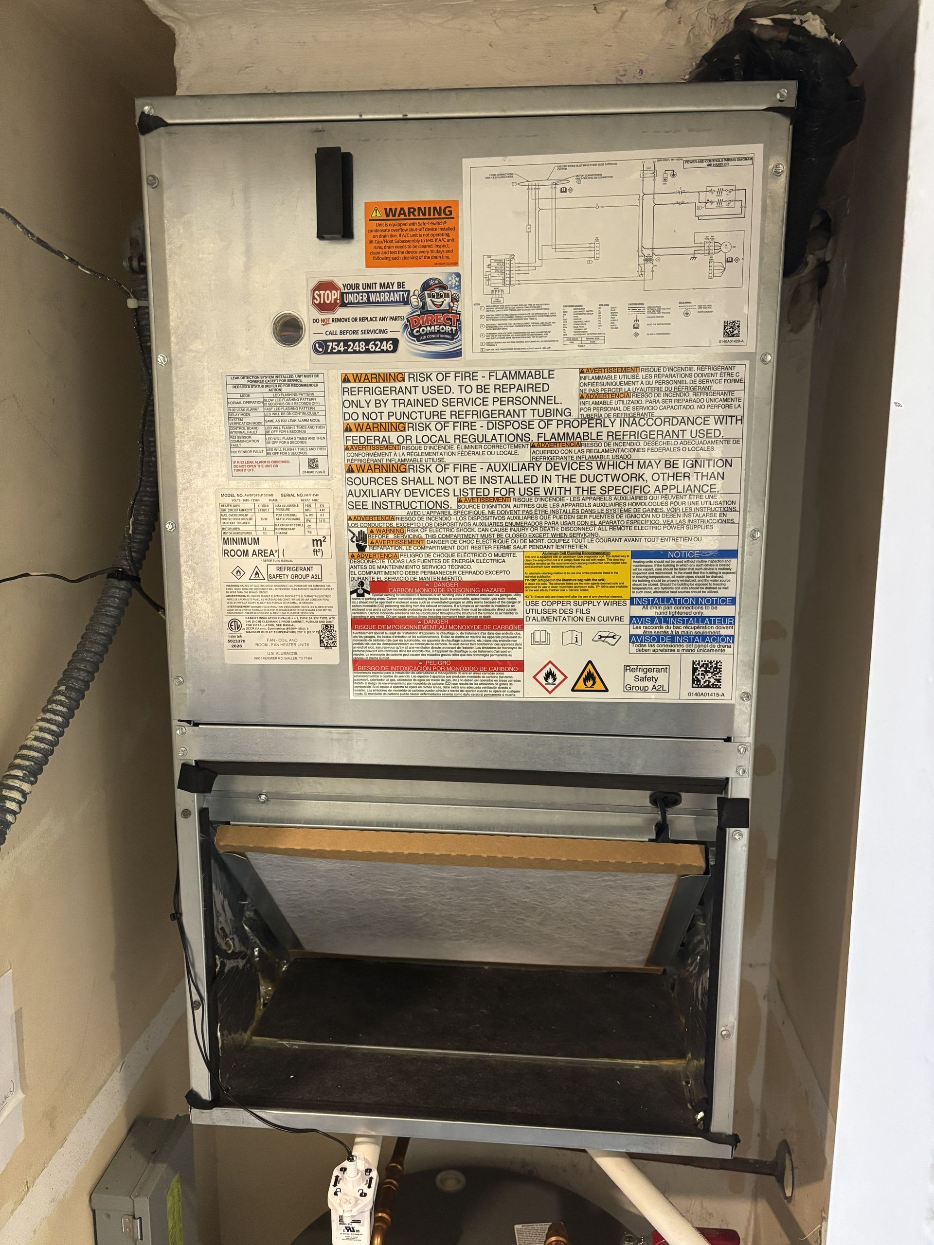 Open electrical panel in a wall, with warning labels and exposed wiring compartment.
