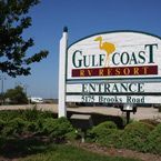 Sign for Gulf Coast RV Resort, white with text in brown and green, a bird graphic, entrance on Brooks Road.