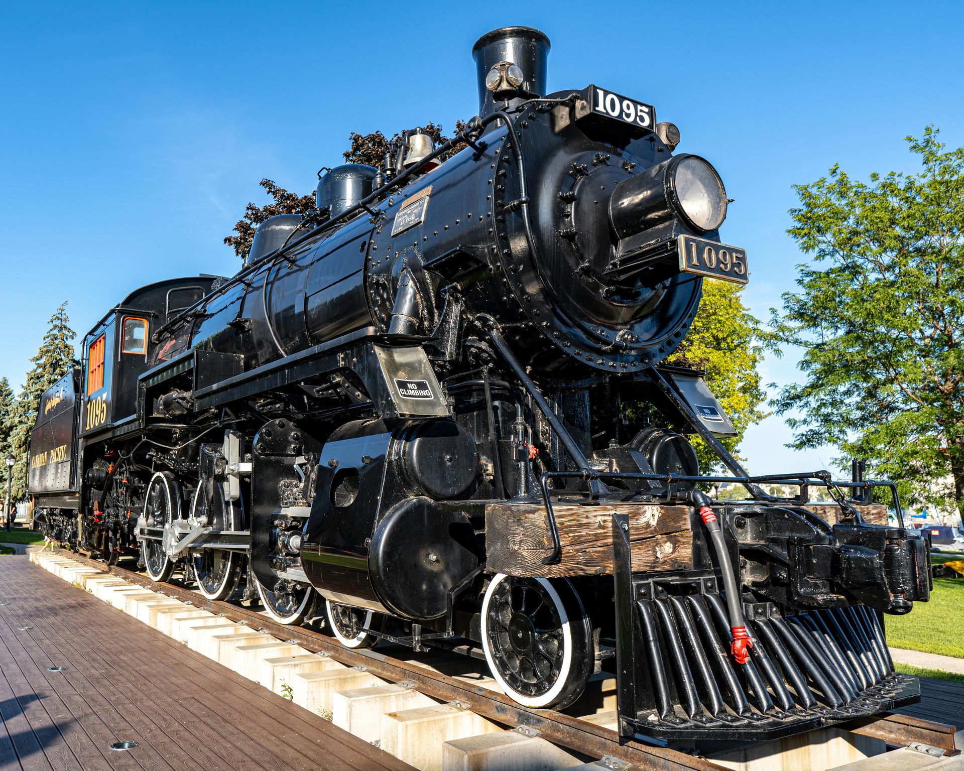 Black steam locomotive on tracks, displaying the number 1093. It sits outdoors in a sunny setting.