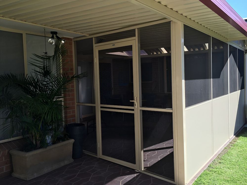 A Screened In Porch With A Door And A Potted Plant — Hunter Home Services in Rutherford, NSW