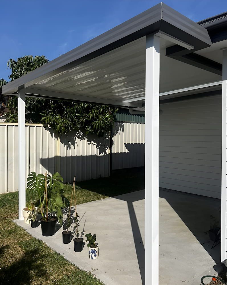 A Patio With A Pergola And Potted Plants In Front Of A House — Hunter Home Services in Lake Macquarie, NSW