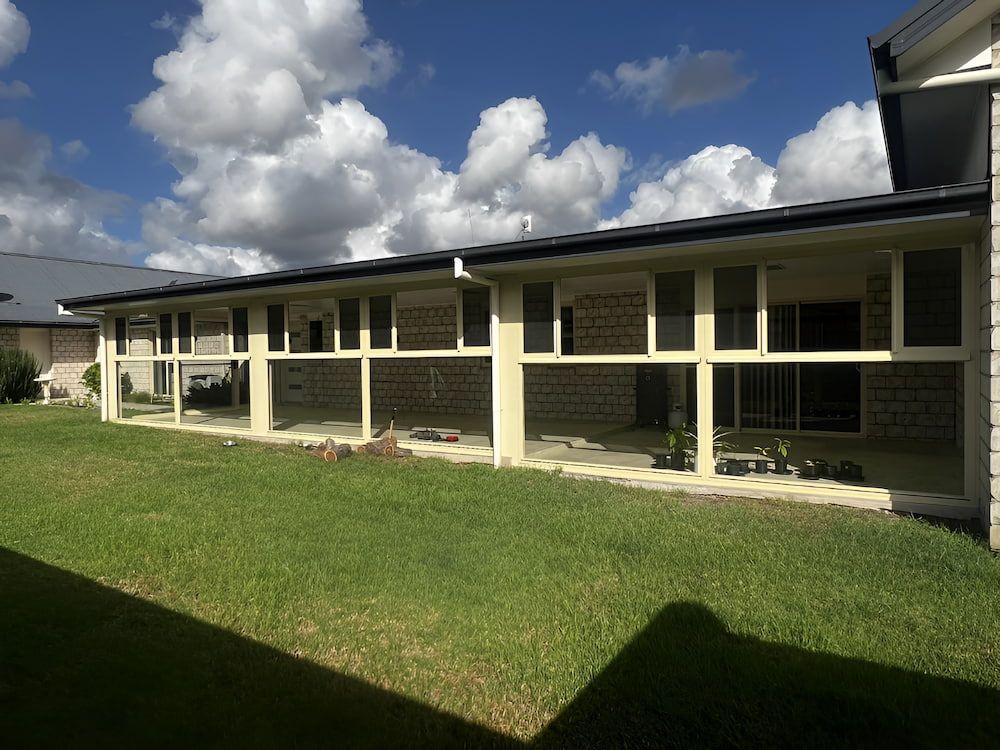 A Large House With A Lot Of Windows And A Lawn In Front Of It — Hunter Home Services in Lake Macquarie, NSW