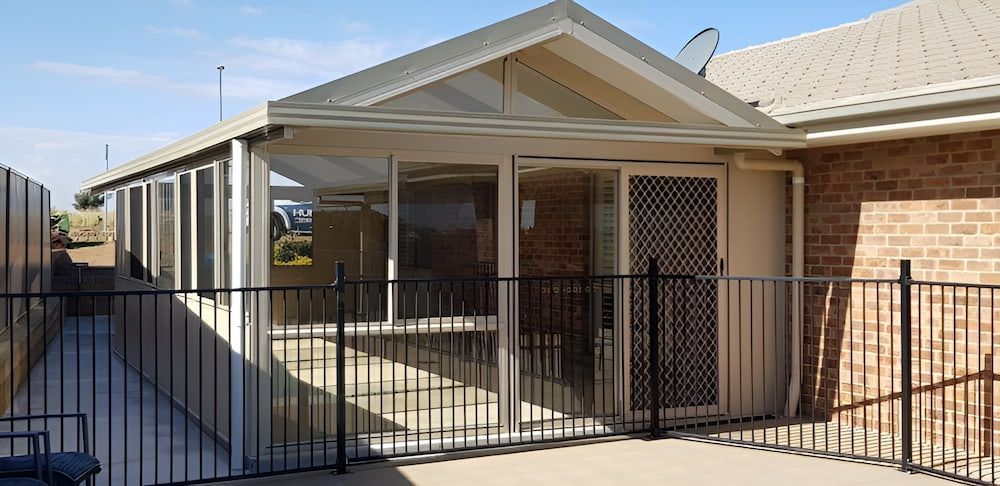 A Covered Patio with A Black Fence, Siding, and A Brick Wall — Hunter Home Services in Lake Macquarie, NSW