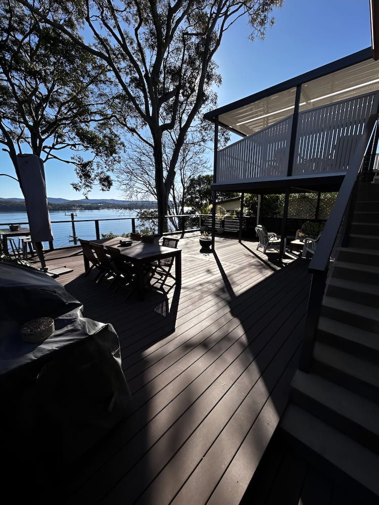 A Deck With Stairs Leading Up To A House Overlooking A Body Of Water — Hunter Home Services in Rutherford, NSW