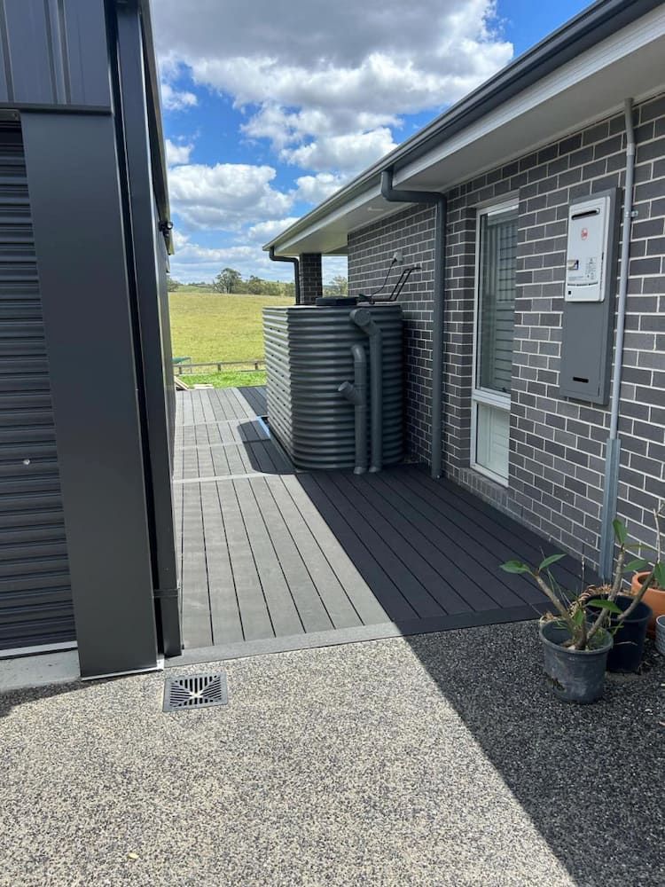 A Brick House With A Deck And A Water Tank On The Side Of It — Hunter Home Services in Huntlee, NSW