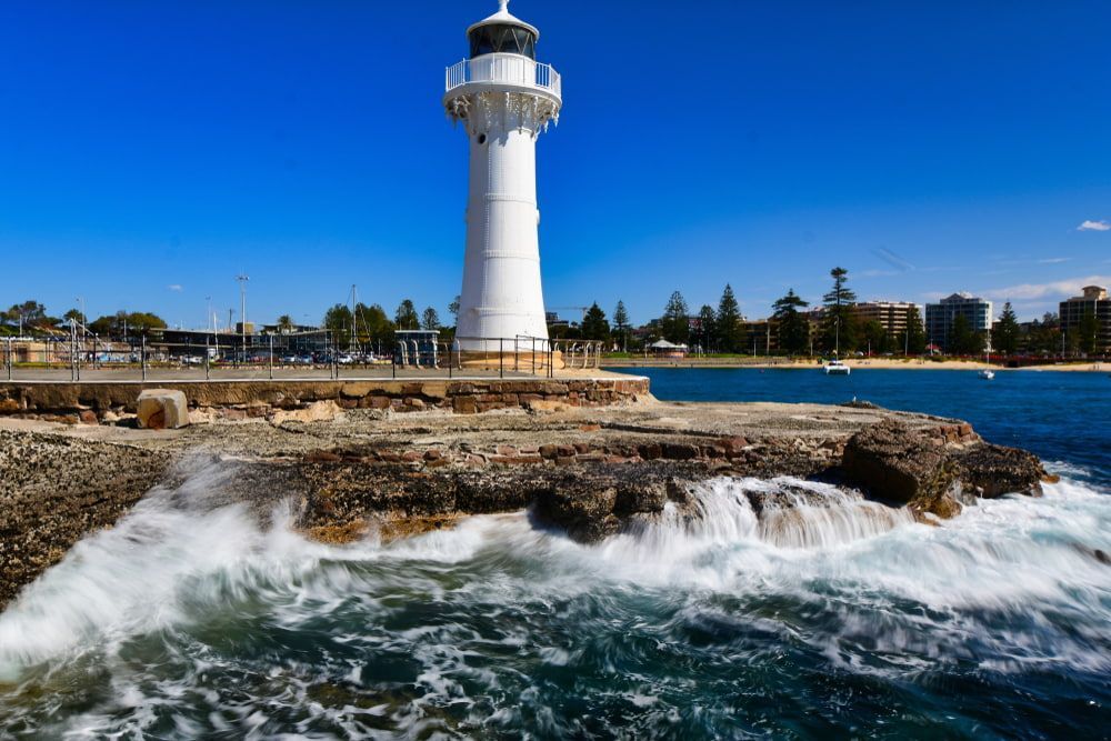 A Lighthouse Is Sitting on Top of A Rocky Cliff Overlooking the Ocean — Leisure Coast Powder Coaters in Wollongong, NSW