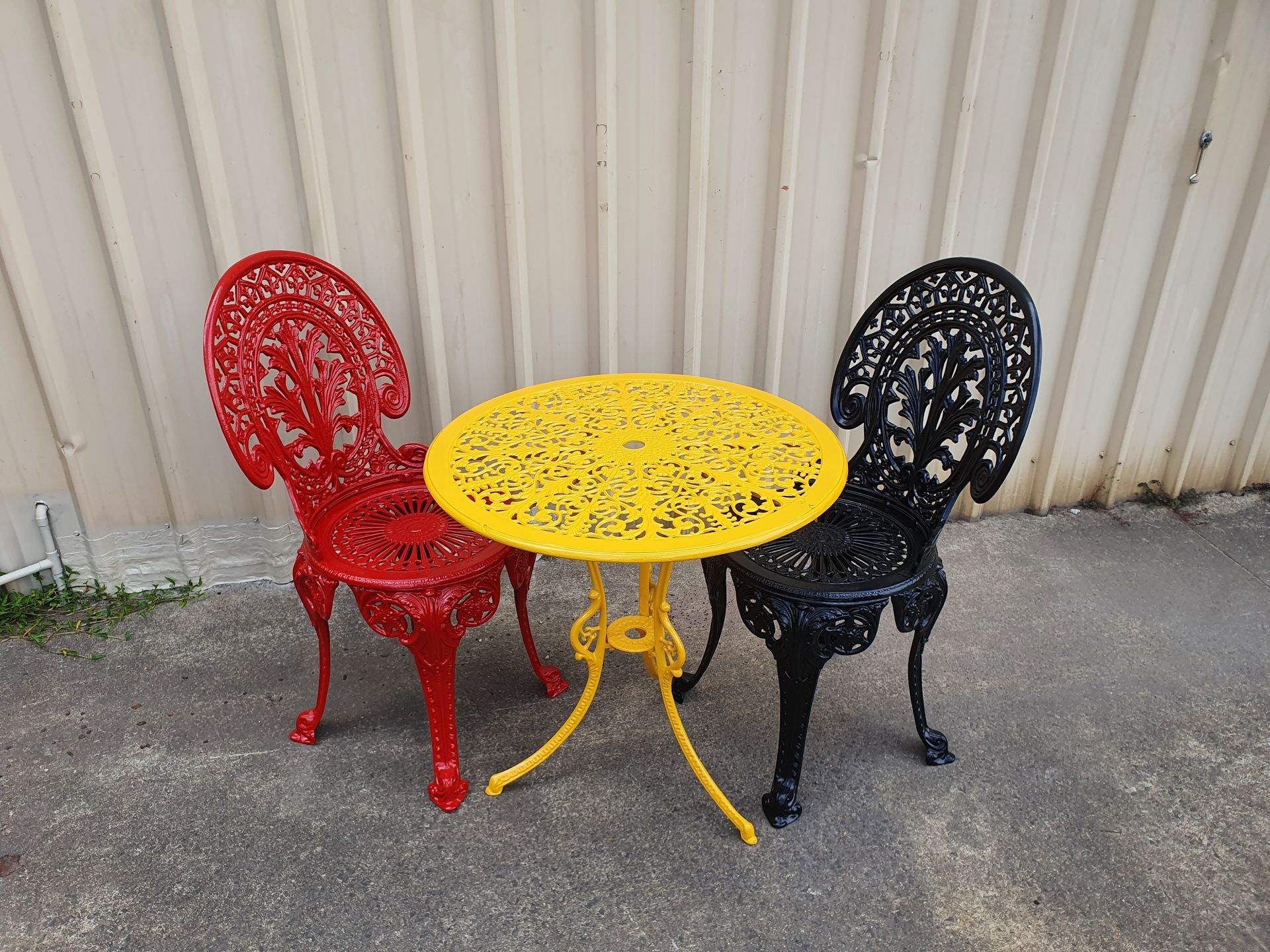 A Yellow Table and Two Red Chairs Are Sitting Next to Each Other — Leisure Coast Powder Coaters in Unanderra, NSW