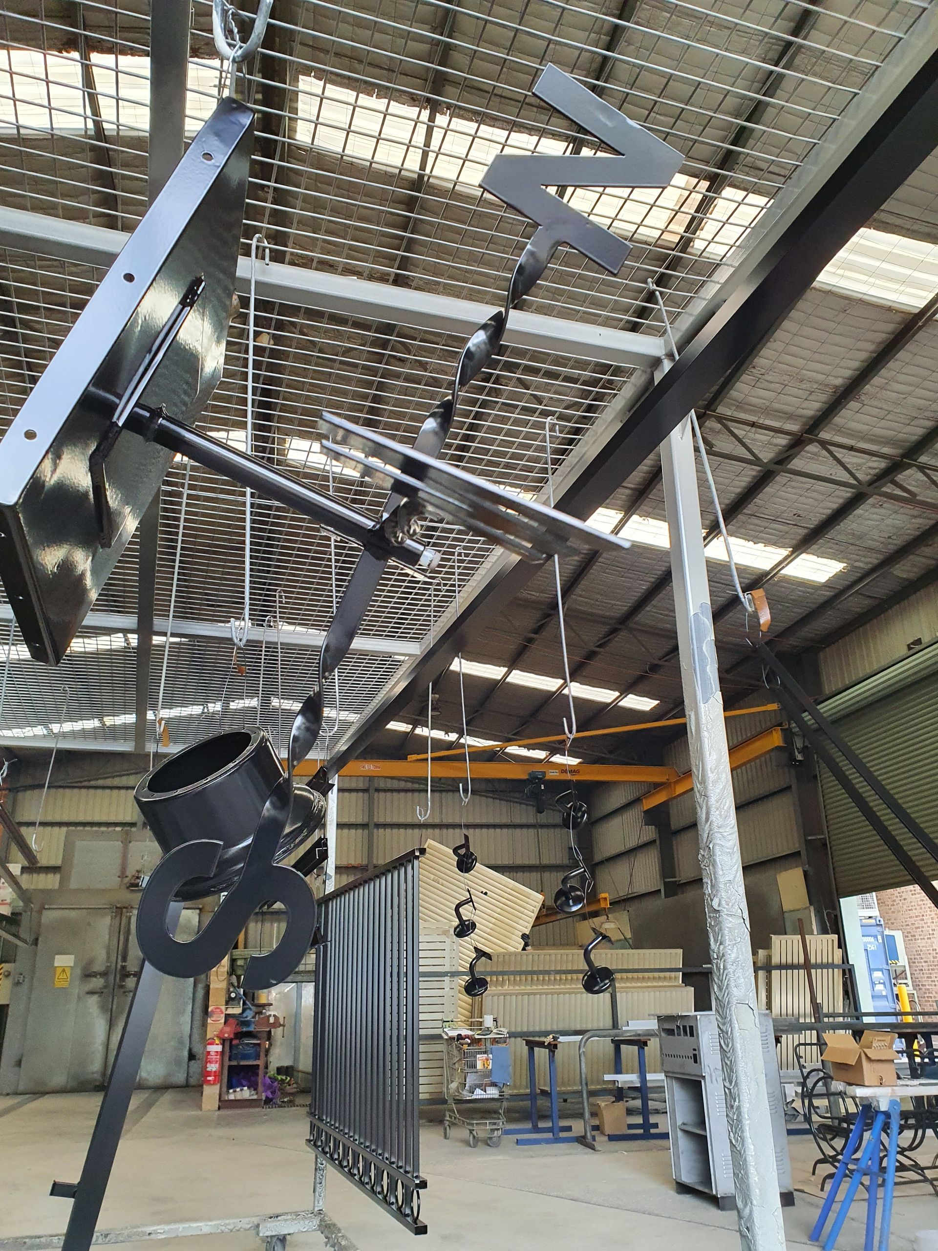 A Warehouse with A Lot of Metal Pieces Hanging from The Ceiling — Leisure Coast Powder Coaters in Unanderra, NSW
