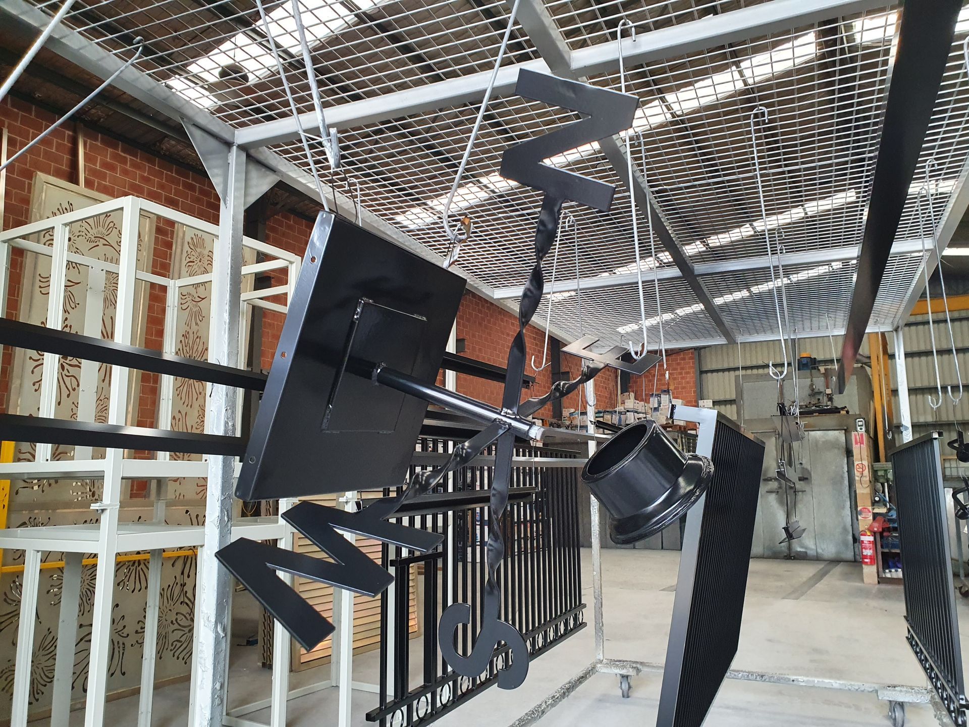 A Warehouse with A Lot of Metal Pieces Hanging from The Ceiling — Leisure Coast Powder Coaters in Unanderra, NSW