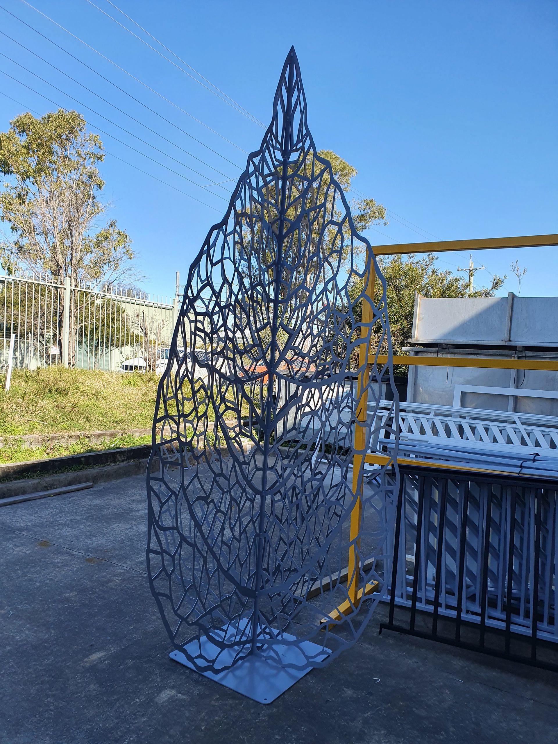 A Large Metal Sculpture of A Leaf Is Sitting on The Ground — Leisure Coast Powder Coaters in Unanderra, NSW