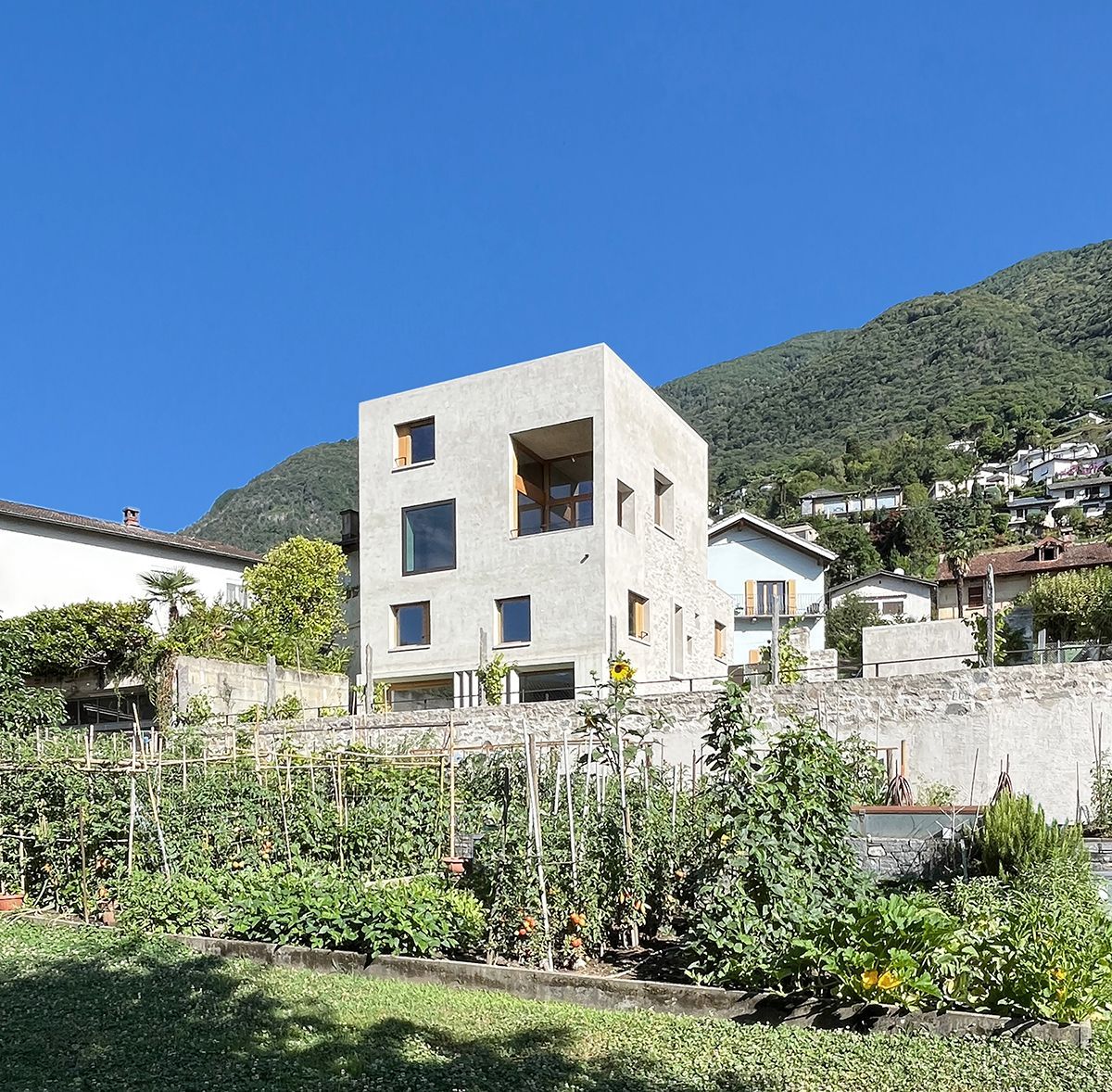 Moderna casa in pietra di notte. Un cubo di cemento grigio scuro sormonta una base in pietra, le finestre illuminate.