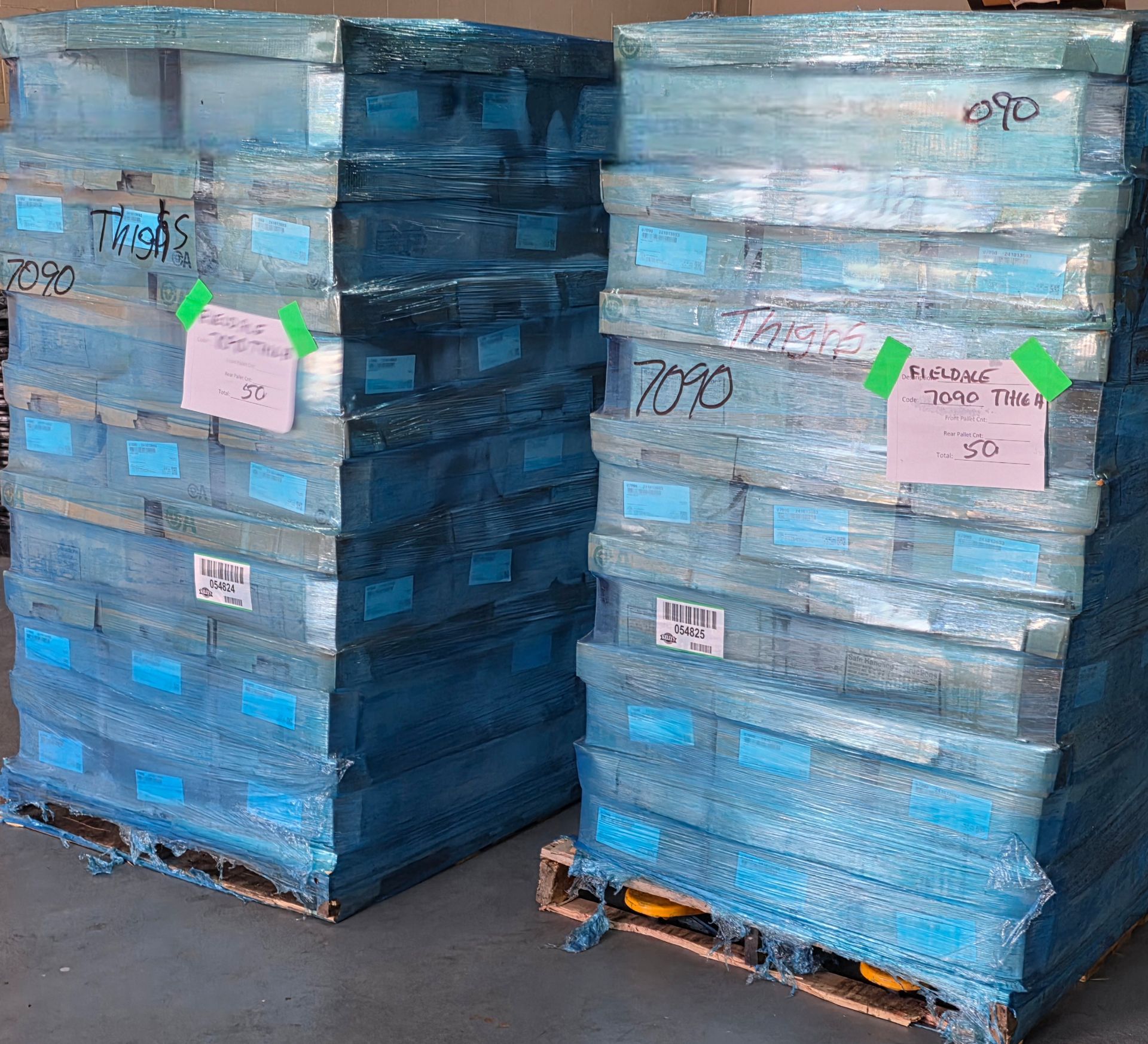 Stacks of blue-wrapped pallets with labels in a warehouse loading area