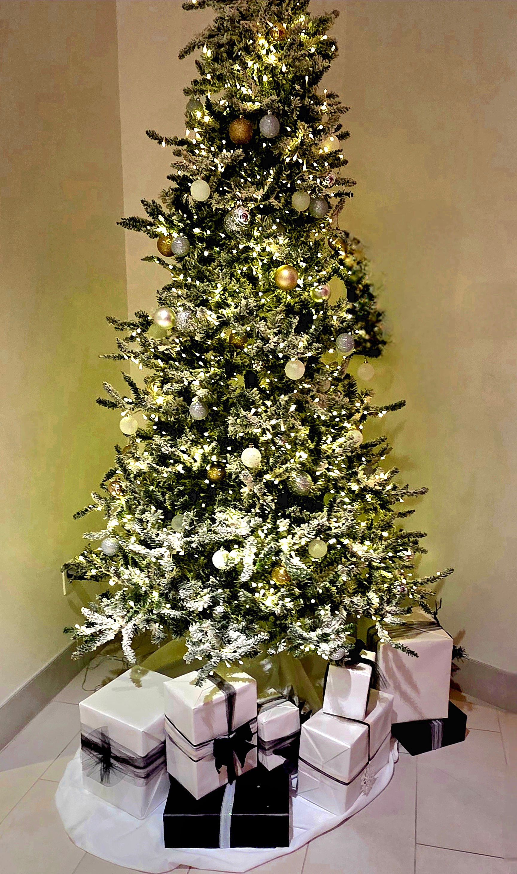Decorated Christmas tree with lights and ornaments, surrounded by wrapped gifts on the floor