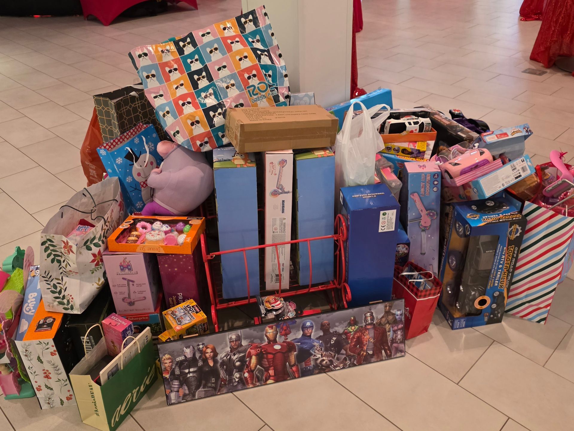 Stacked colorful gift boxes and toys arranged on a tiled floor in a store-like setting