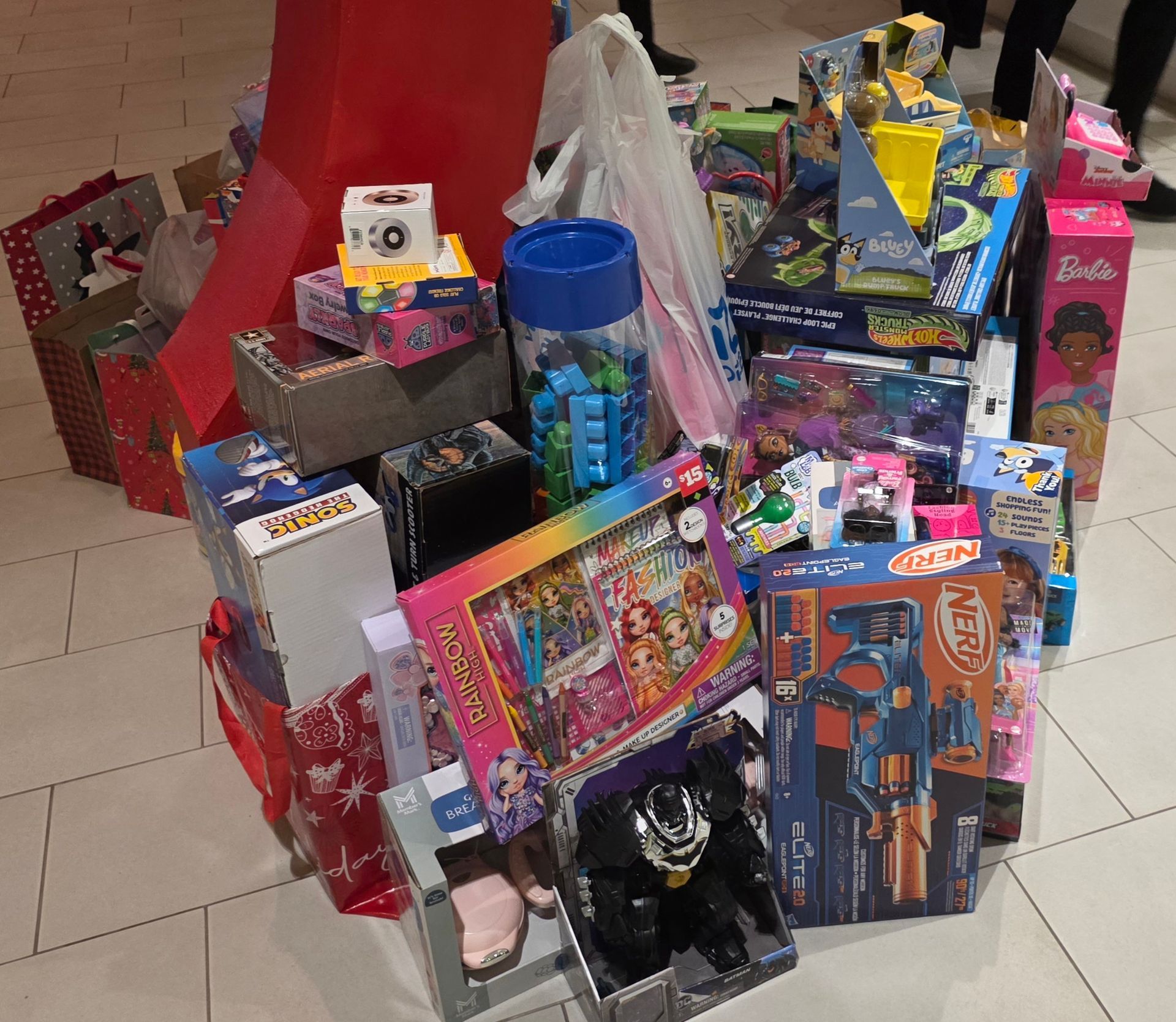 Piles of brightly wrapped gift boxes and toys arranged on a tiled floor in a room