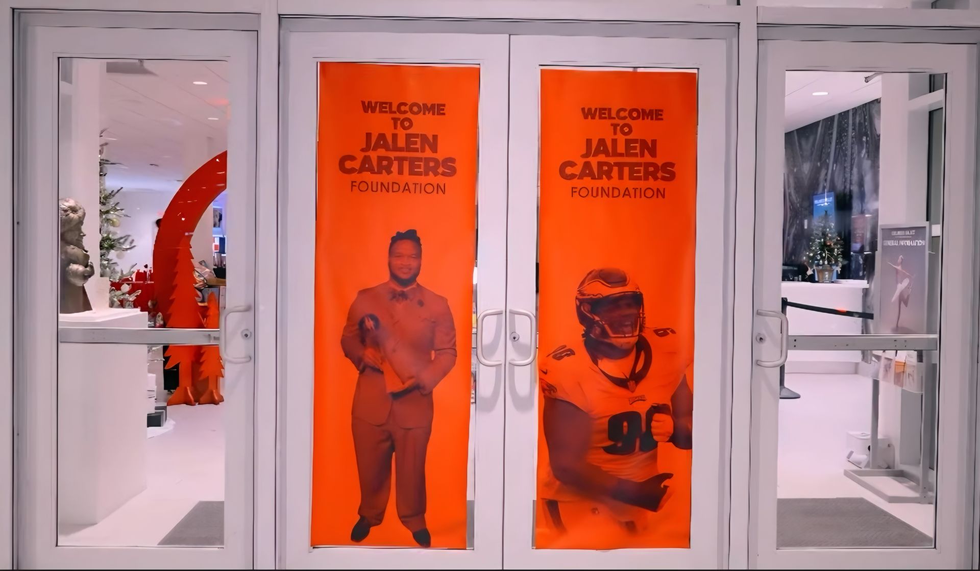 White entrance with two orange “Welcome Jalen Carter” posters and glass doors.